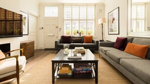 Una sala de estar con sofá, sillón, mesa de centro y televisor.