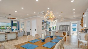 Un vaste espace dédié à la salle à manger, avec une table en bois, des sets de table bleus et un lustre.