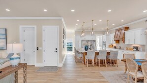 Une cuisine moderne avec des meubles blancs, un îlot central et des luminaires suspendus.