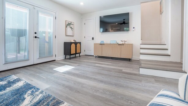 A modern living room with a wooden floor, a sofa, a cabinet, and a staircase. - Spacious 4-bedroom house in Fort Walton Beach with lots of parking. (Fort Walton Beach)