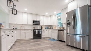 A modern kitchen with white cabinets, stainless steel appliances, and a wooden floor. - Spacious 4-bedroom house in Fort Walton Beach with lots of parking. (Fort Walton Beach)