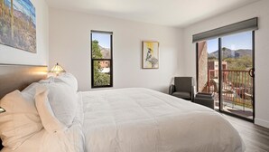 Ein Hotelzimmer mit einem Bett, einem Sessel, einem Balkon mit Bergblick und Kunstwerken an den Wänden.