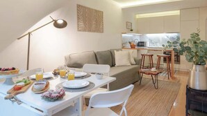 Ein modernes Wohnzimmer mit Essbereich, einer Couch und einer Küche im Hintergrund.