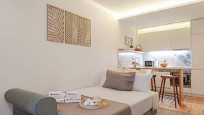 Ein kleines Hotelzimmer mit Bett, Schreibtisch und Kochnische.
