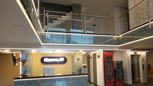 A modern hotel lobby with a reception desk, a staircase, and a glass railing. - New Hotel Vip (Bogotá)