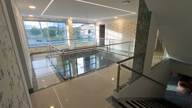A modern interior with a glass railing, a tiled floor, and a view of the outside. - New Hotel Vip (Bogotá)