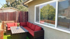 A patio with a wicker sofa, red cushions, and a small table.