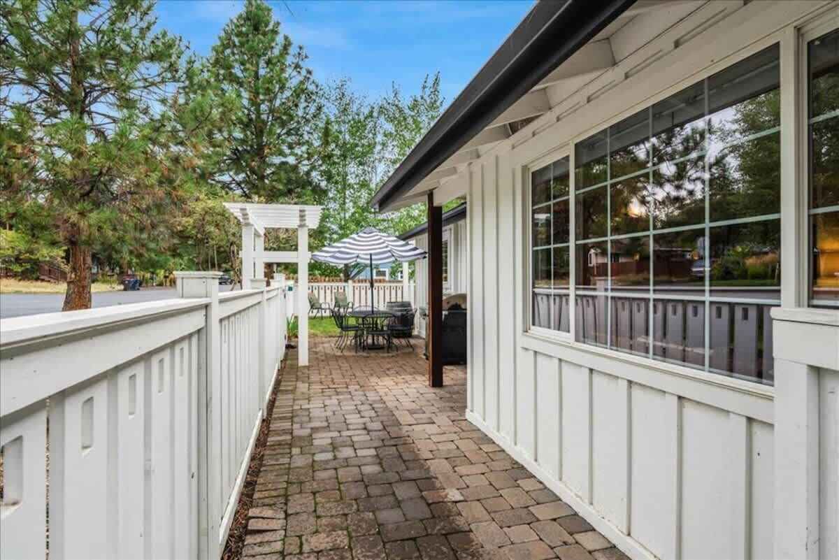 A covered patio area with a pergola, outdoor seating, and a view of the surrounding trees.