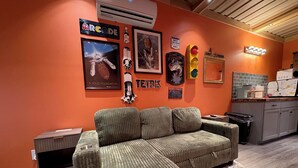 Ein Zimmer mit einer Eckcouch, einem kleinen Tisch, einem Mülleimer und einer Küchenzeile mit Spüle und Arbeitsfläche.