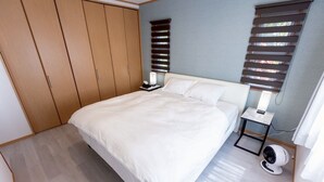 A bedroom with a bed, a bedside table, a fan, and a wardrobe. - Exclusive view of the star-filled sky on the rooftop terrace. Walking distance from Imgarma Marine Garden (1.1km). Privileges: Free Miyako soba noodles, BBQ set rental, and star photography can be arranged. Unattended check-in support. (Miyaknjima)