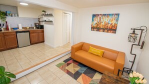 Een moderne keuken met houten kastjes, een vaatwasser en een zithoek met een bank en een tafel.