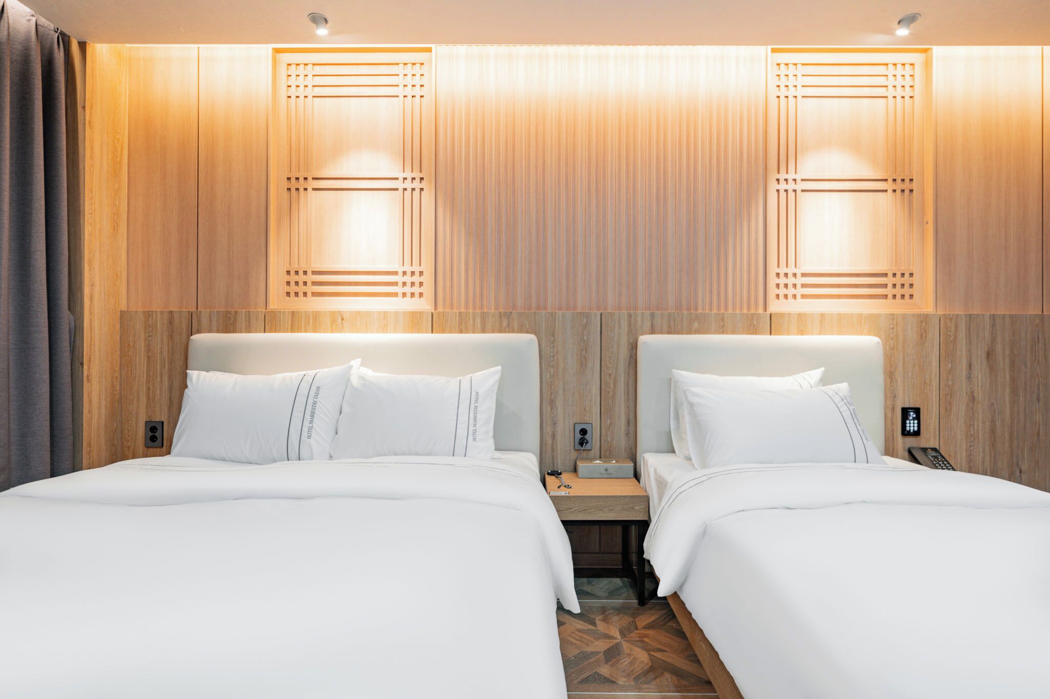 Habitación de hotel con dos camas, paneles de madera y un diseño moderno.