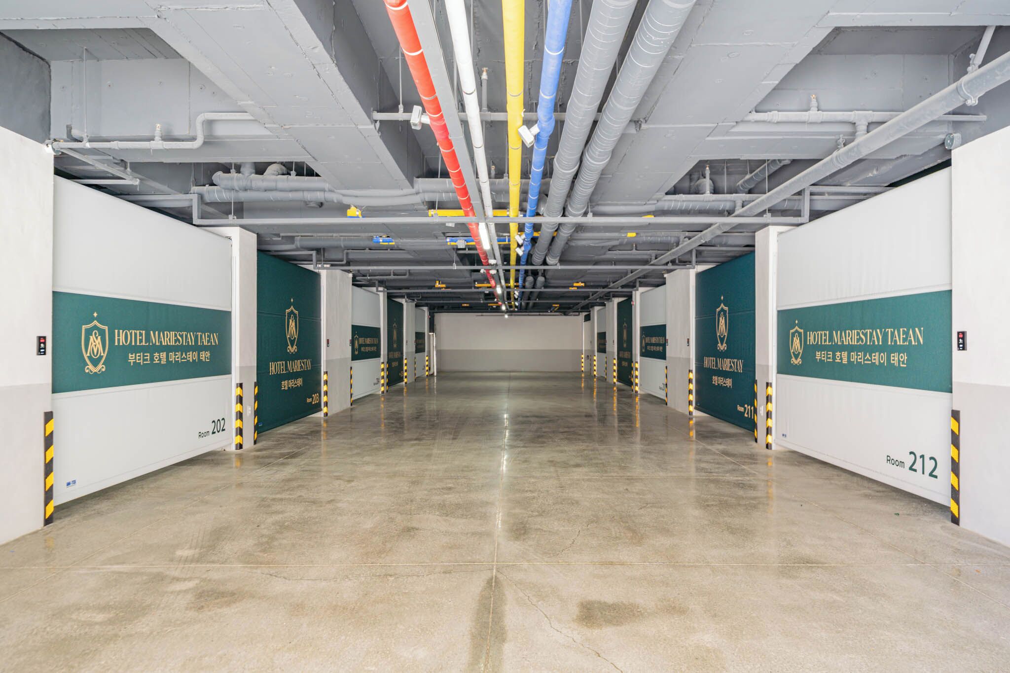 A clean, modern hotel corridor with multiple rooms, including rooms 202 and 212, and visible HVAC ducts.