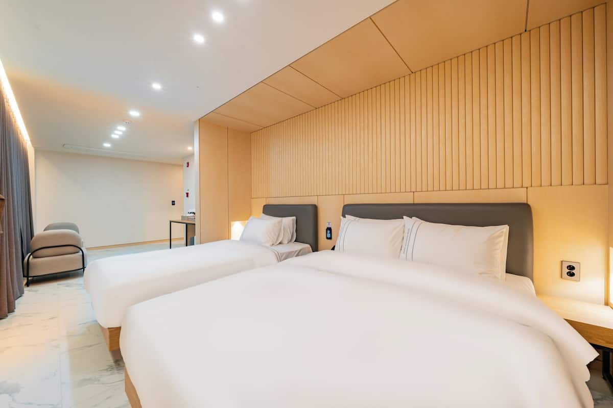 A hotel room with two beds, a desk, and a chair.