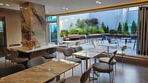 A modern indoor dining area with marble walls, a variety of seating options, and a view of an outdoor garden. - HOTEL MARIESTAY TAEN (Taean)