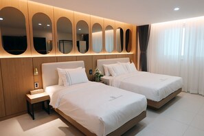 Une chambre d’hôtel avec deux lits, une tête de lit en bois, une table de chevet et un mur entièrement recouvert de miroirs.