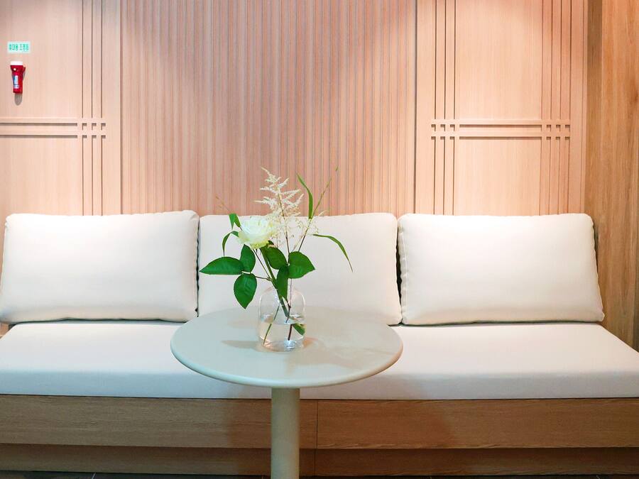 A modern hotel room with a white sofa, a small round table, and a vase with flowers.