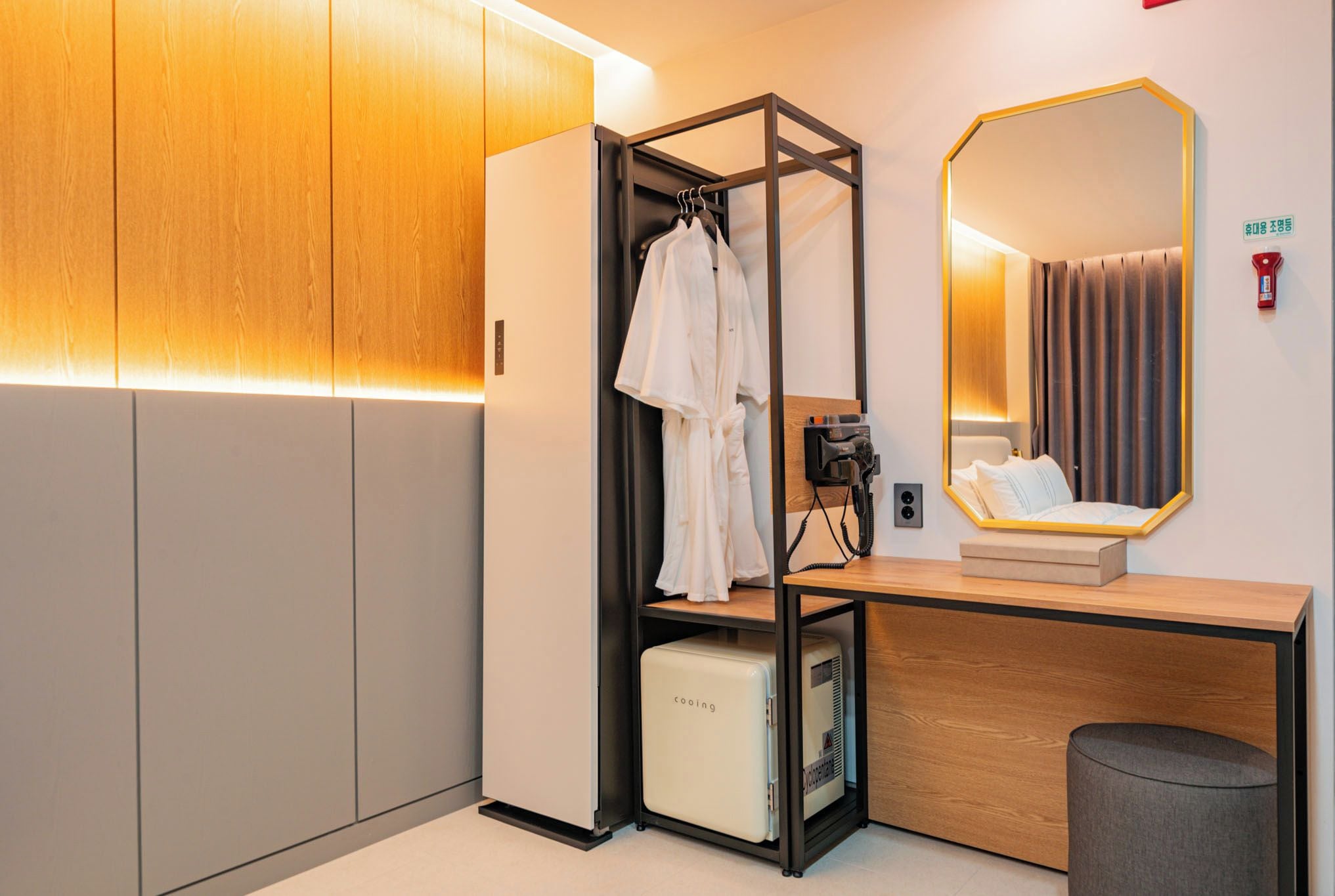 Un bagno moderno con un mobile bagno in legno, uno specchio, un porta asciugamani e un piccolo climatizzatore.