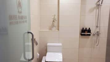 A bathroom with a toilet, a shower, and a small shelf with toiletries.
