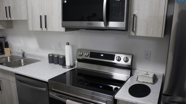 A modern kitchen with stainless steel appliances, including a microwave, oven, and refrigerator. - New basement suite in Saskatoon's newest neighborhood. Welcome to the Casa! (Saskatoon)