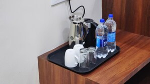 A tray with a coffee maker, two water bottles, and a white mug on a wooden counter. - Hotel Robo Nest (Balichauki)