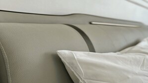 Gros plan d’un canapé dont le revêtement est en cuir lisse de couleur claire, et dont on peut voir la couture.