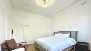 Et moderne soveværelse med seng, stol, natbord og gulvlampe.