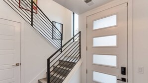 A staircase with a black metal railing, a white door with frosted glass panels, and a window above the door.