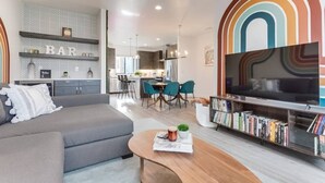 A modern living room with a grey sofa, a coffee table, a bookshelf, and a TV.