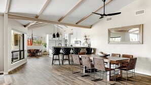 Un vaste espace dédié à la salle à manger, avec une table et des chaises en bois, un ventilateur de plafond et un grand miroir accroché au mur.