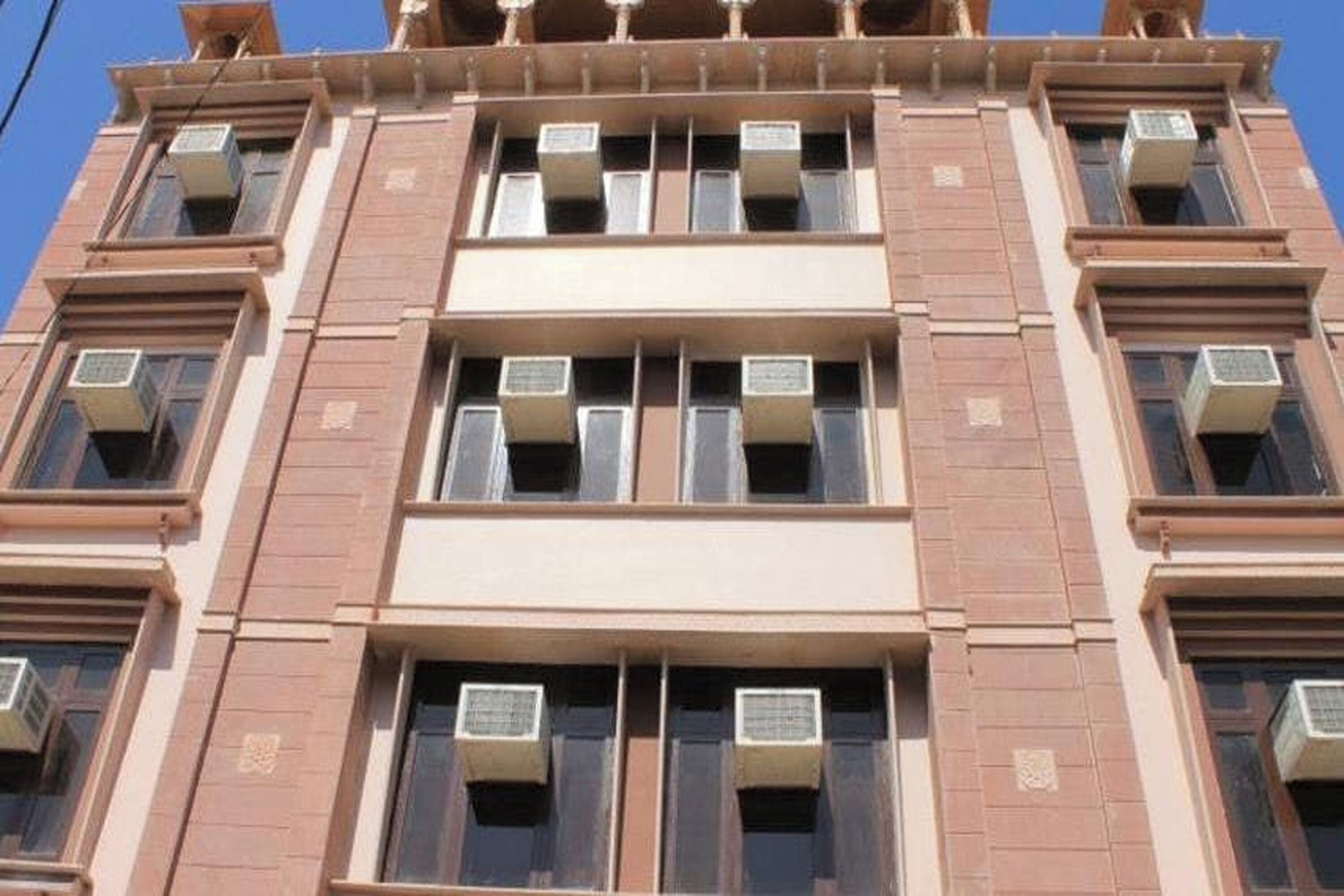 A multi-story building with air conditioning units installed in the windows.