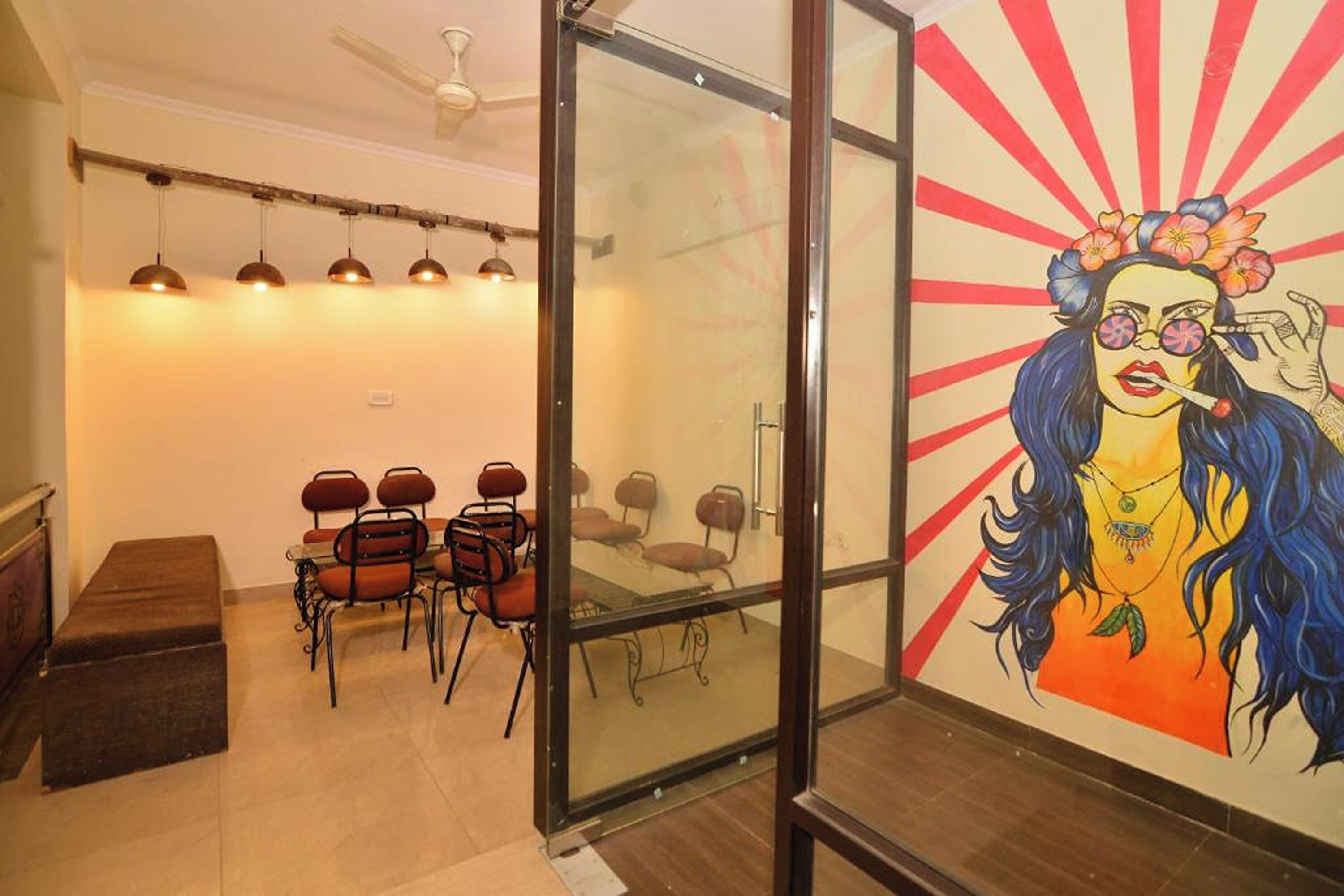 A conference room with a glass partition, a ceiling fan, and a mural on the wall.