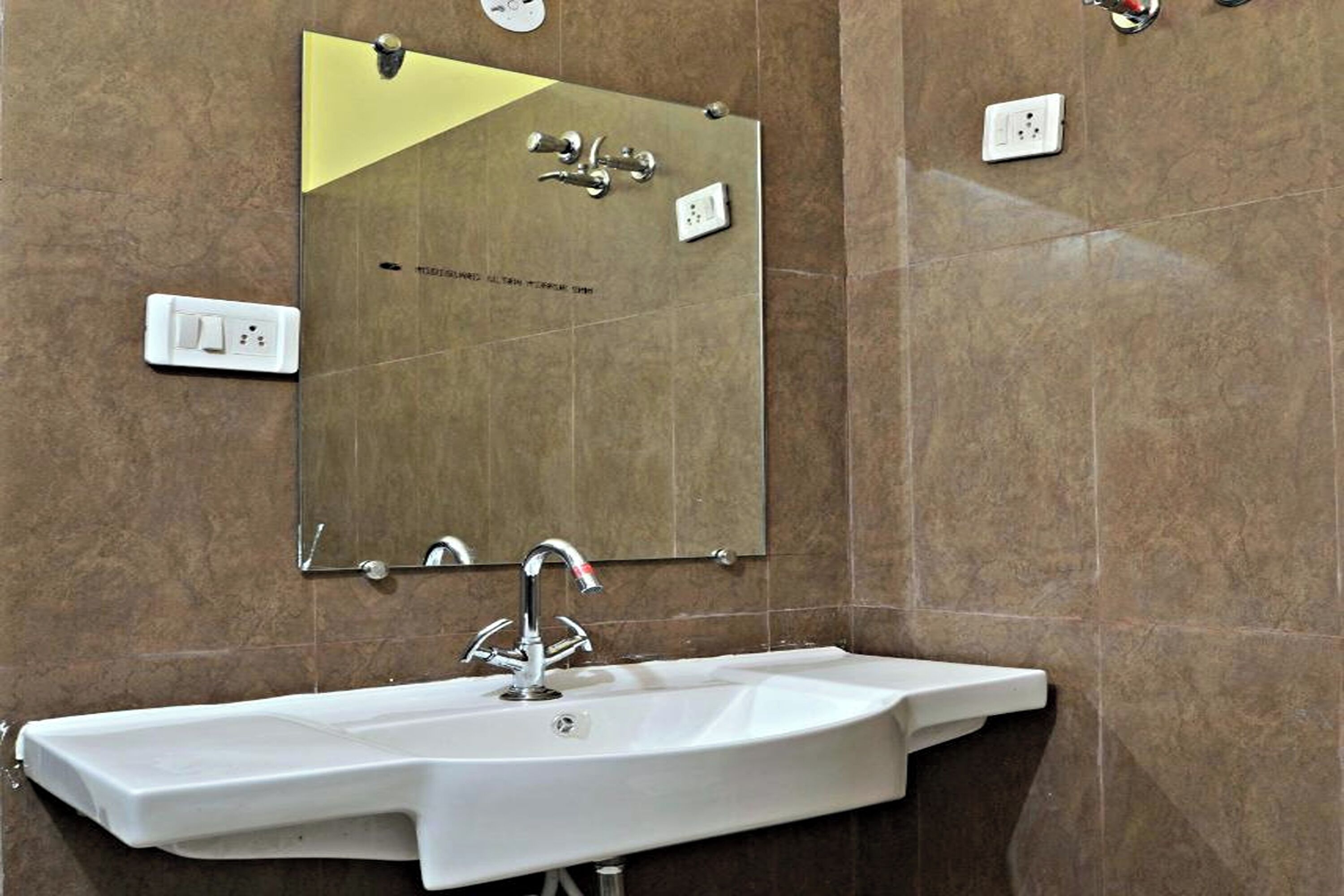 Un baño con un lavamanos blanco, un espejo y un perchero para toallas.
