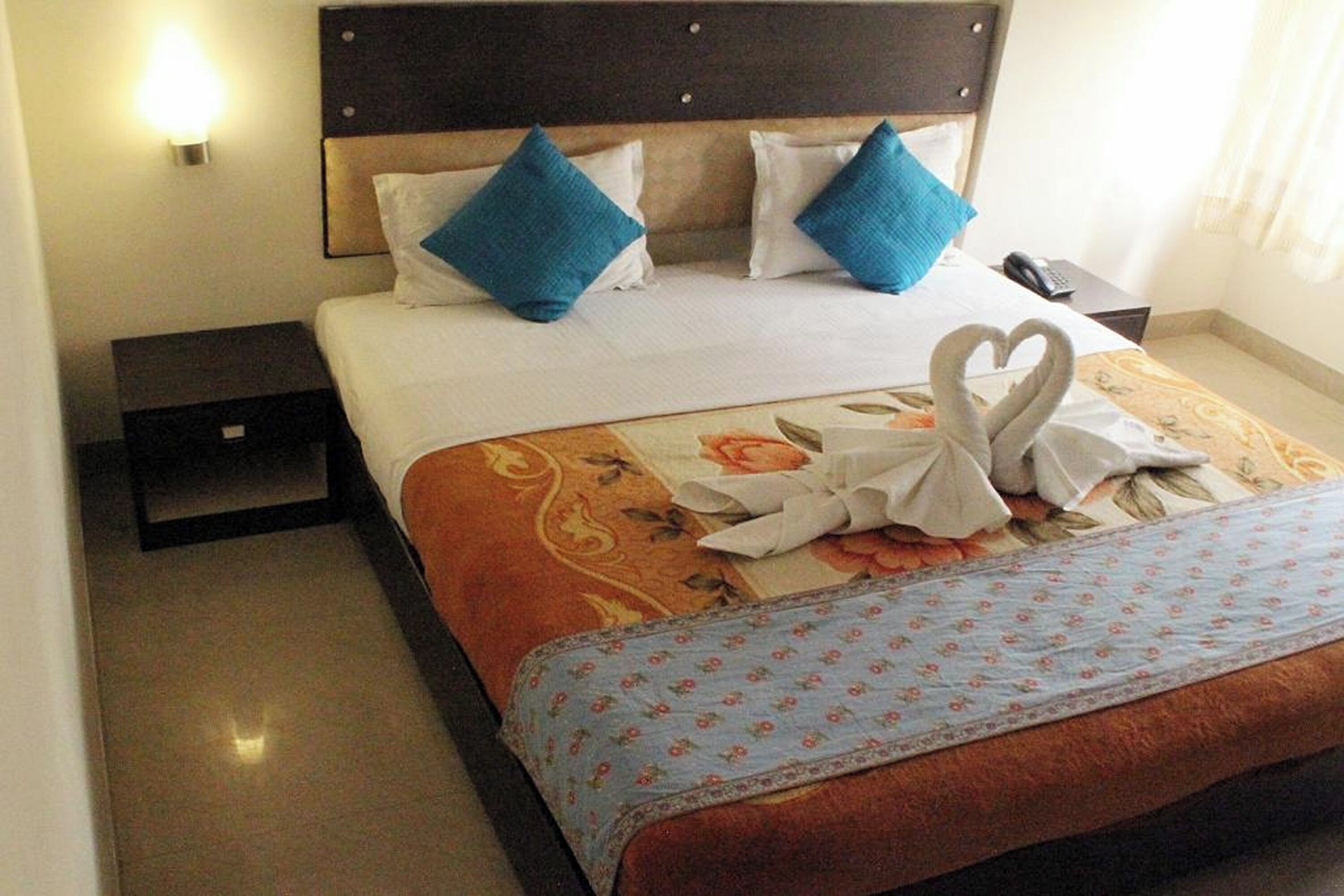 A hotel room with a bed, a nightstand, a lamp, and a telephone.