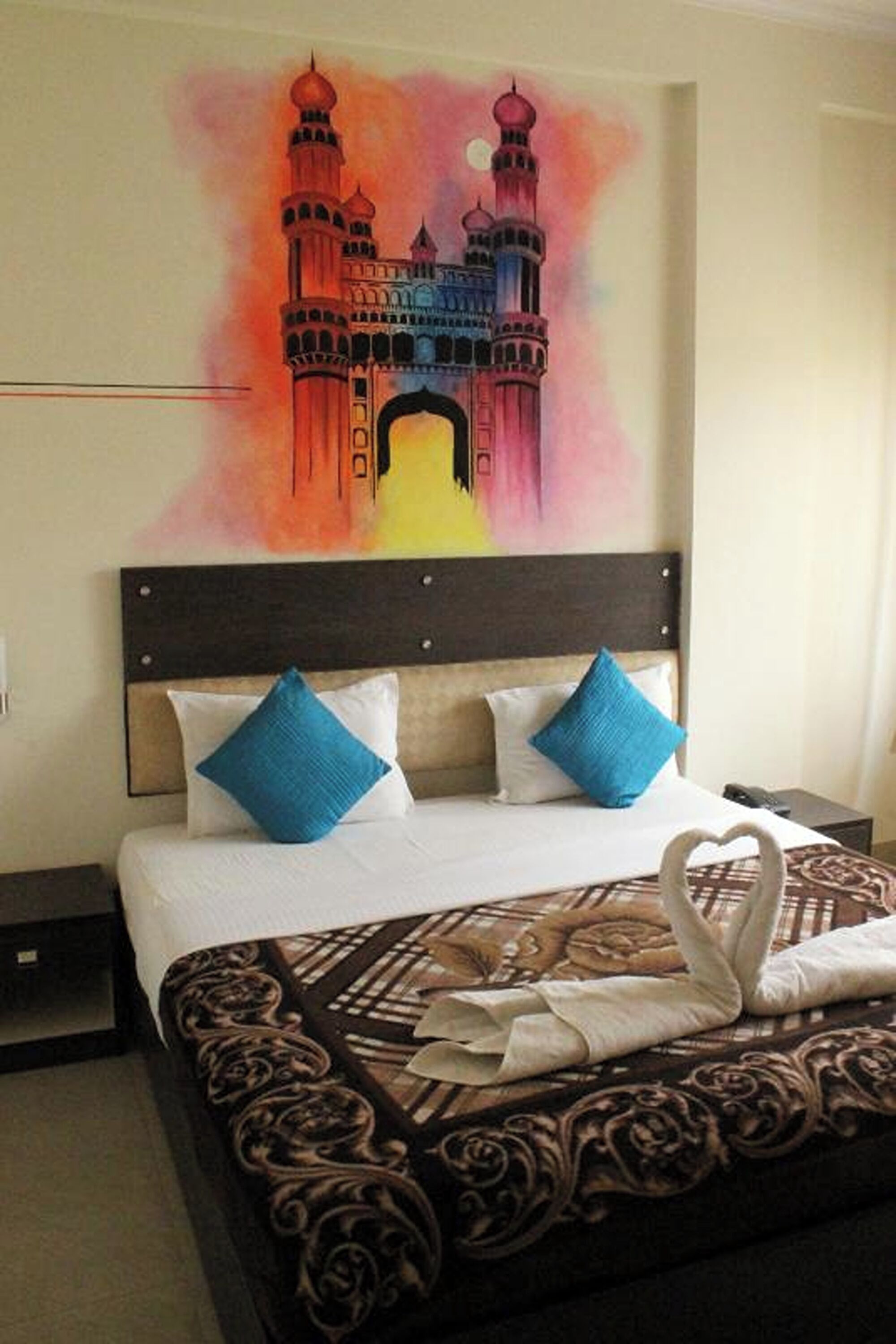 Una habitación de hotel con una cama, una mesita de noche y un cuadro de un edificio en la pared.