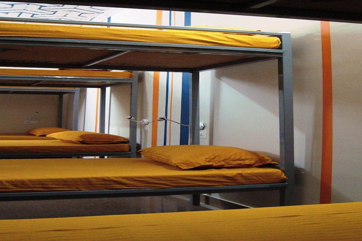 Habitación con literas dobles, cada una con colchón y almohada amarillos.
