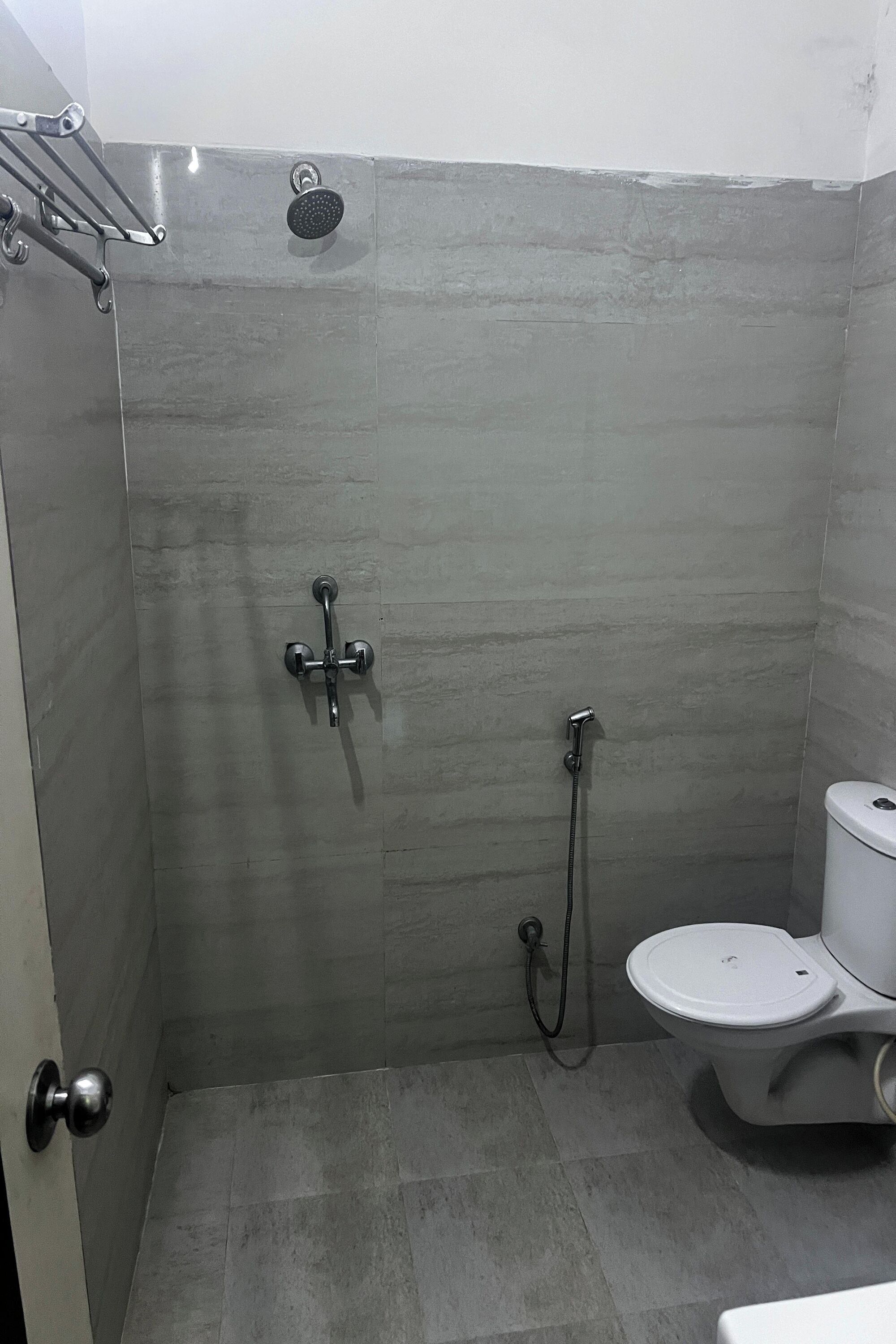 A small, modern bathroom with a shower, toilet, and a towel rack.