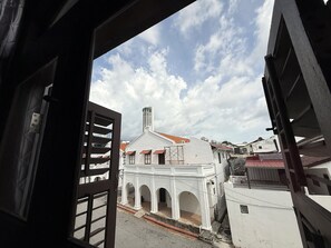 A view through an open door of a building with white walls and red-tiled roofs, featuring a central arched structure and a tall chimney. - Carnarvon Heritage Lodge (George Town)