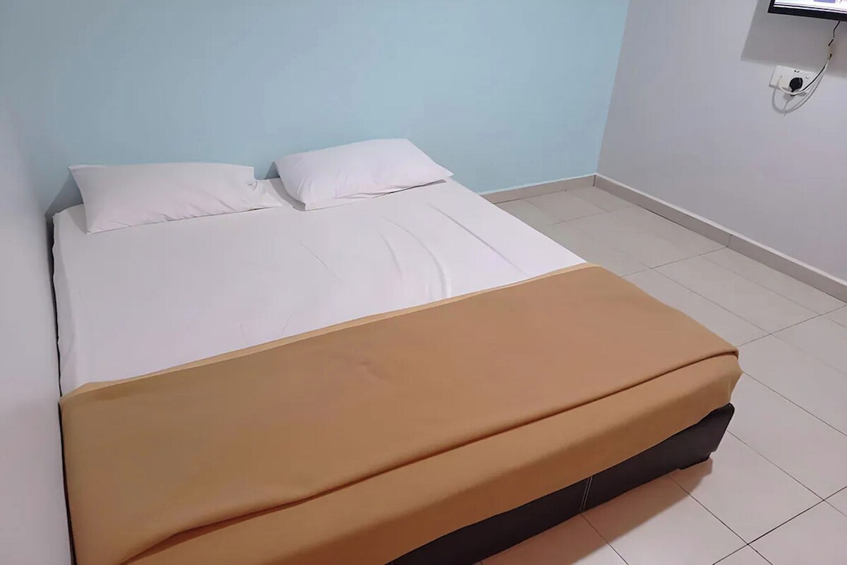 A bed with white bedding and a brown blanket, a light blue wall, and a tiled floor.
