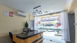 A reception desk with a computer, a small plant, and a view of the street outside.