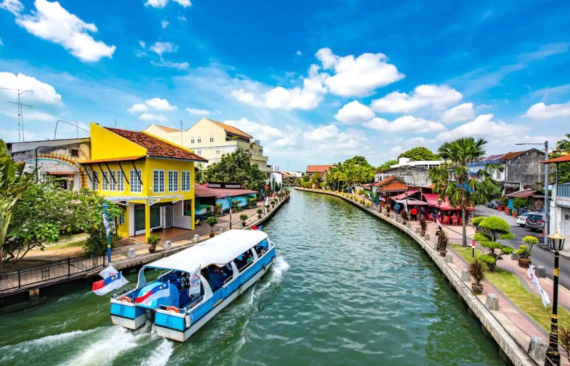 A narrow waterway with a boat, buildings on either side, and a clear sky.