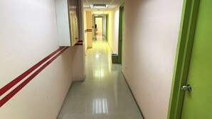 A long, narrow hallway with a shiny tiled floor and walls painted in light colors with red and green accents. - Angsa Hotel (Seremban)