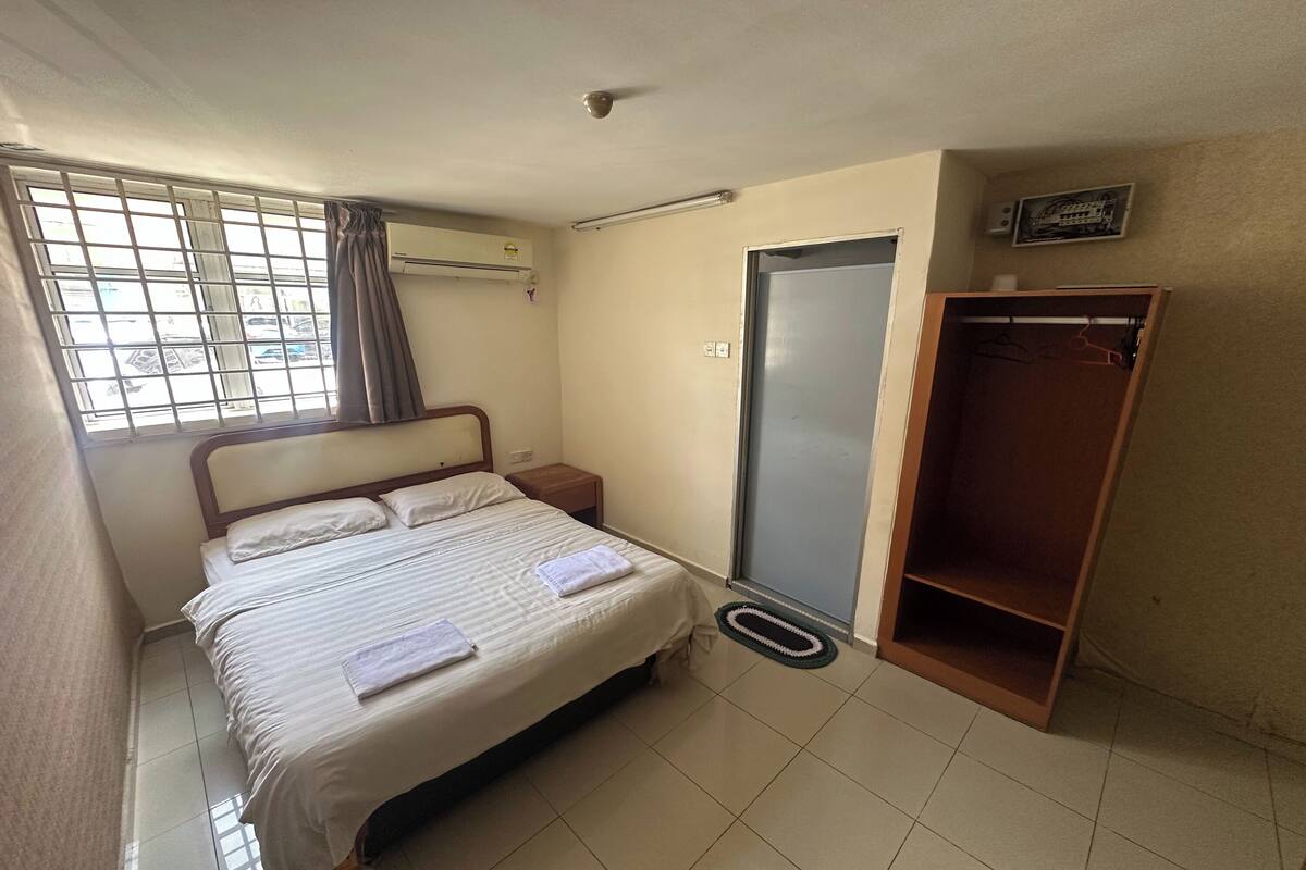 A bedroom with a bed, a wardrobe, a door, and a window with curtains.