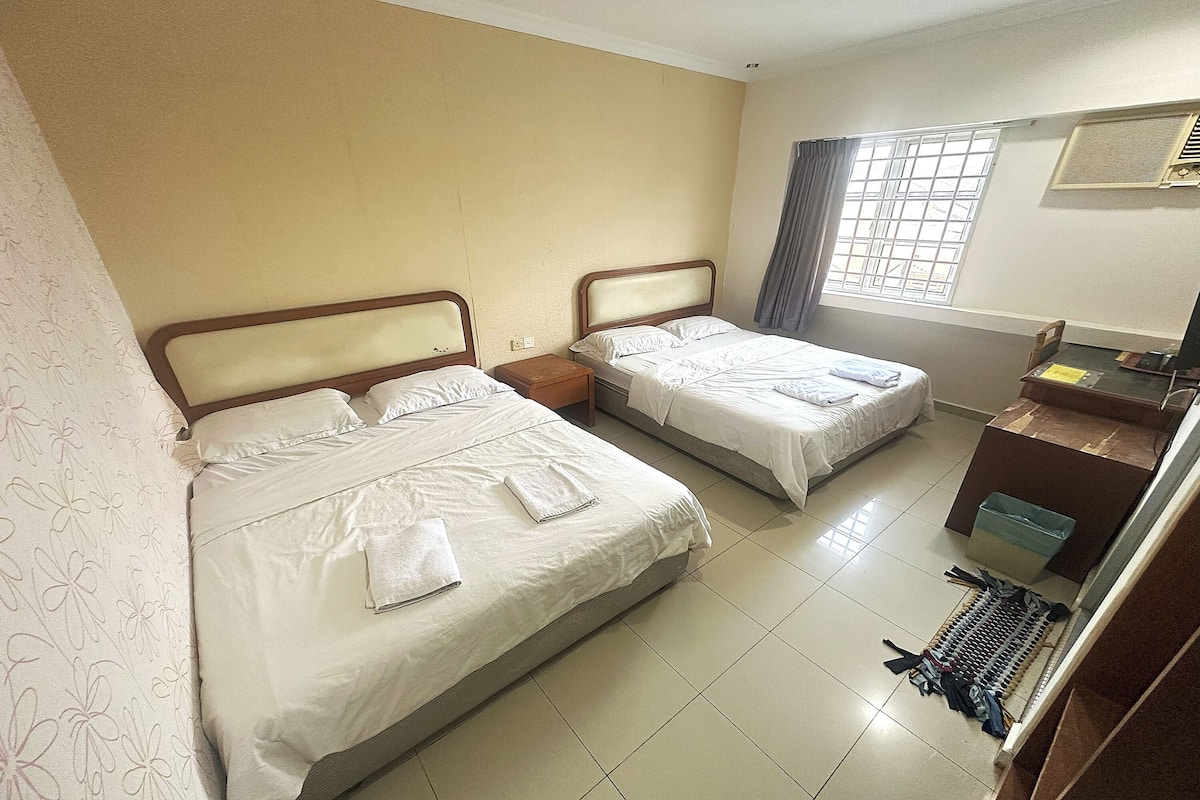 A hotel room with two beds, a desk, and a window with curtains.