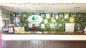 A reception desk with framed certificates and a green wall. - Angsa Hotel (Seremban)