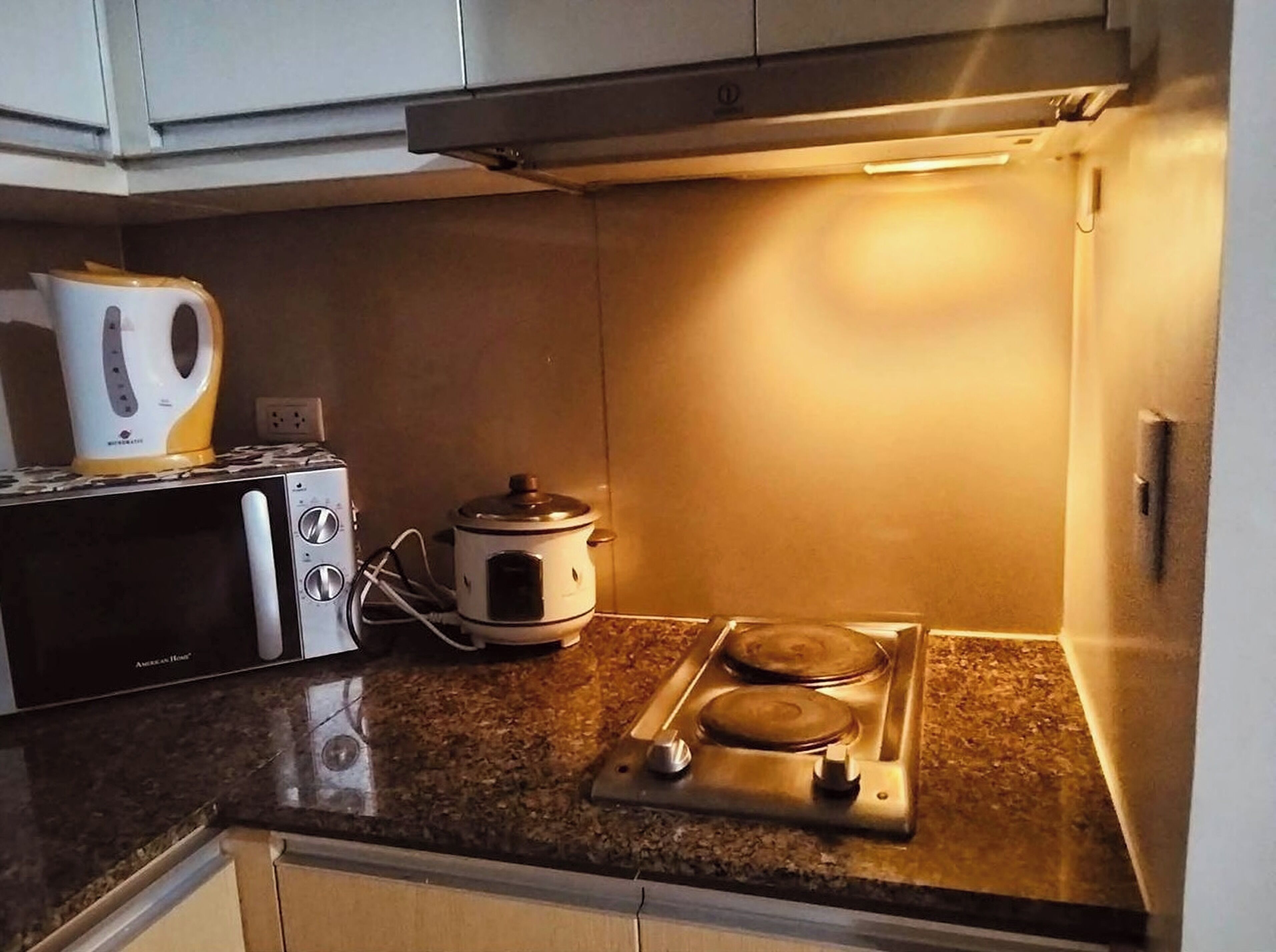 A compact kitchen with a microwave, a slow cooker, and a gas stove.