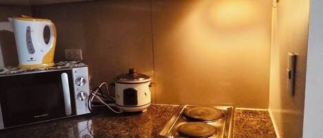 A compact kitchen with a microwave, a slow cooker, and a gas stove.