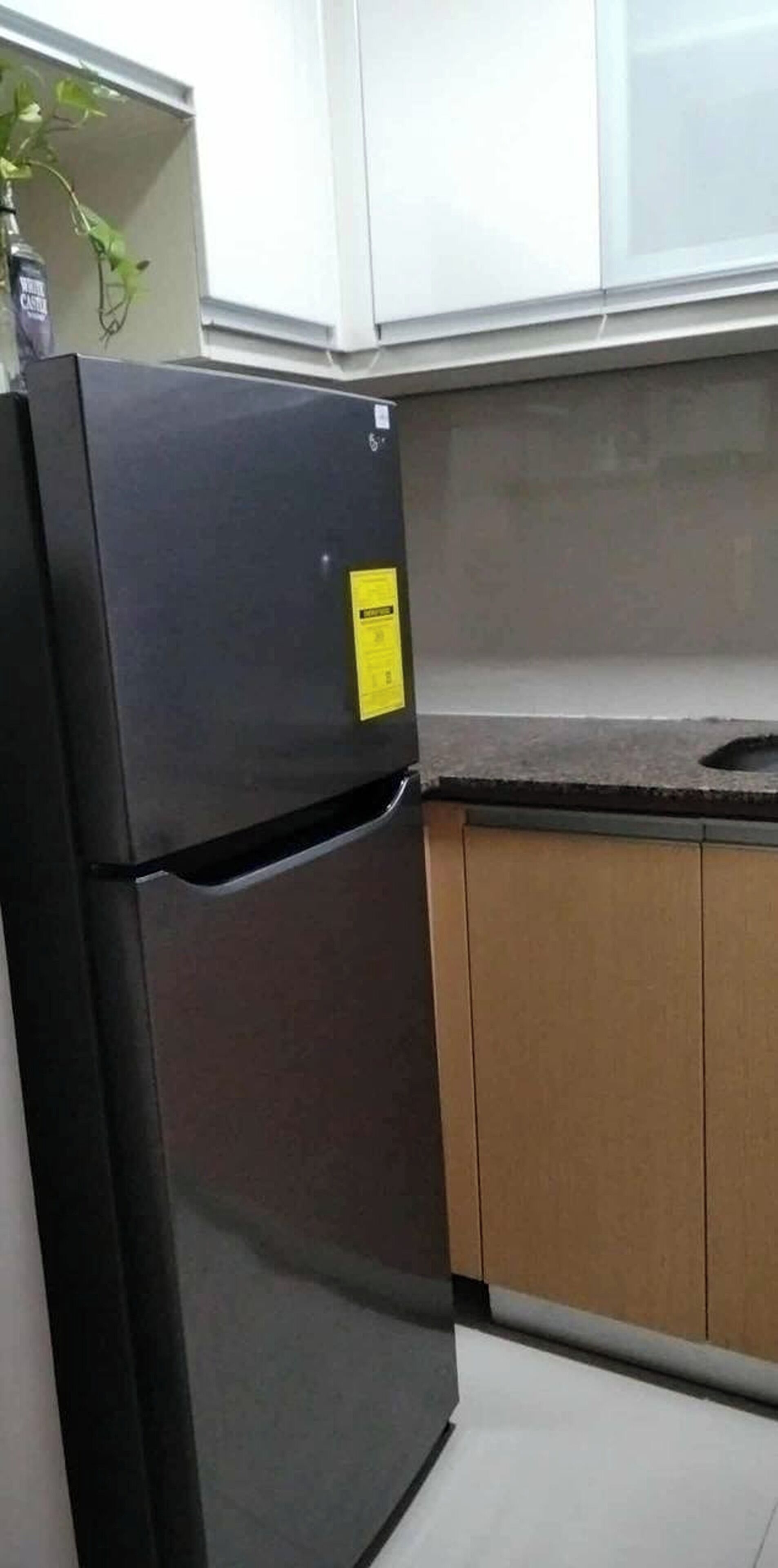 Una cocina con un refrigerador negro, armarios de madera y una encimera.