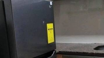 Una cocina con un refrigerador negro, armarios de madera y una encimera.