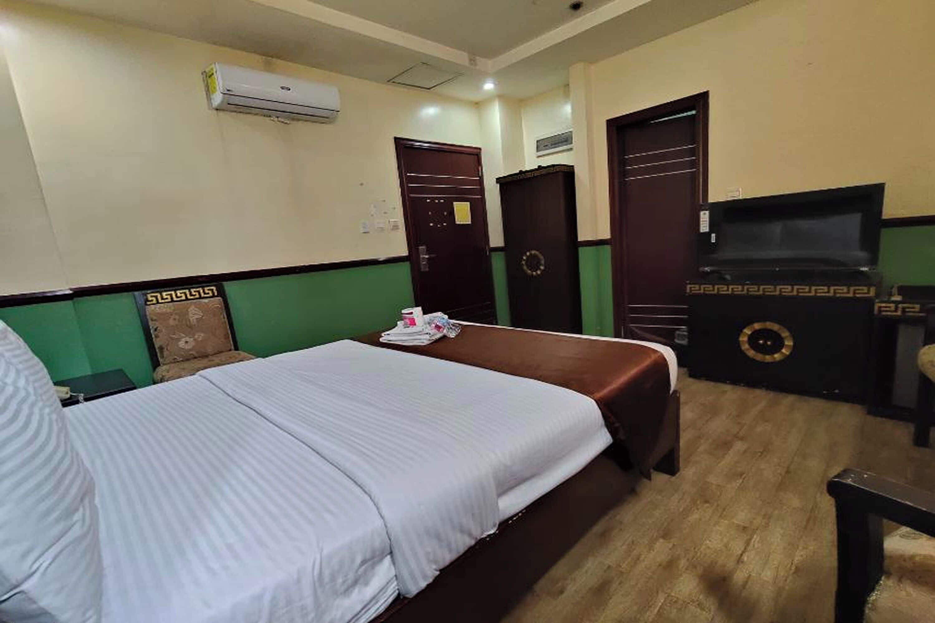 Een hotelkamer met een bed, een televisie, een bureau en een kledingkast.